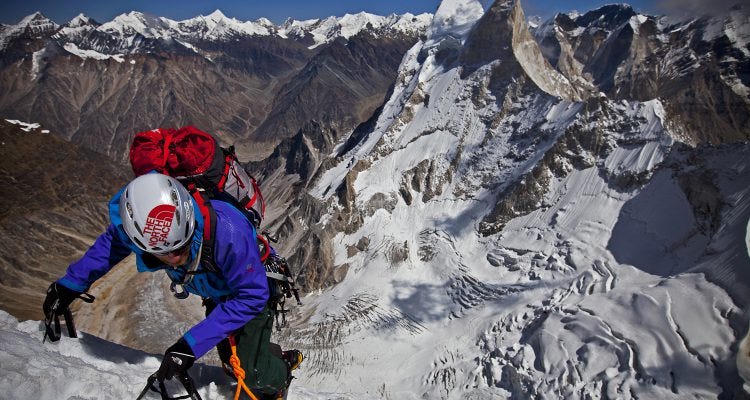 Conrad Anker climbing out fully geared up with helmet and hiking backpack.